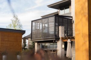Modern elevated sunroom enclosure attached to a luxury home.