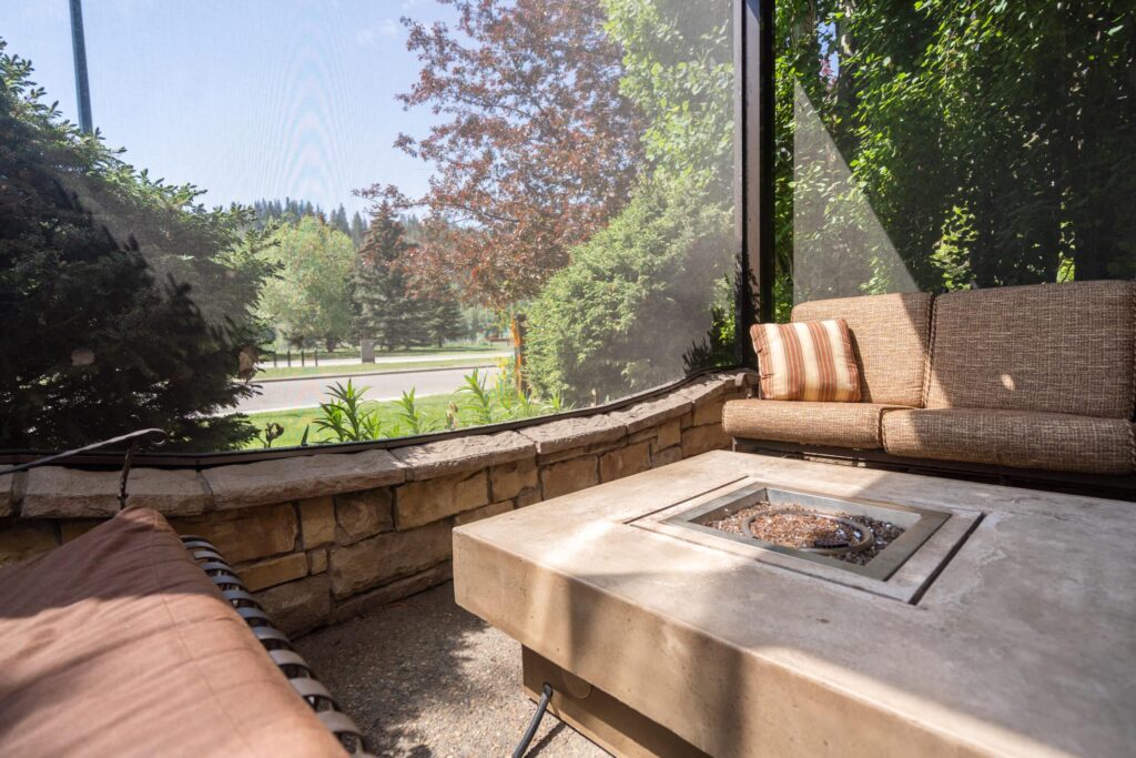 Screened patio with cushioned seating and modern fire table.